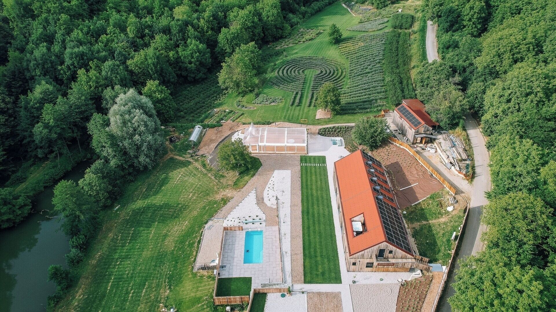 Vue aérienne d’une propriété dotée d’une piscine, d’un court de tennis et d’une serre.