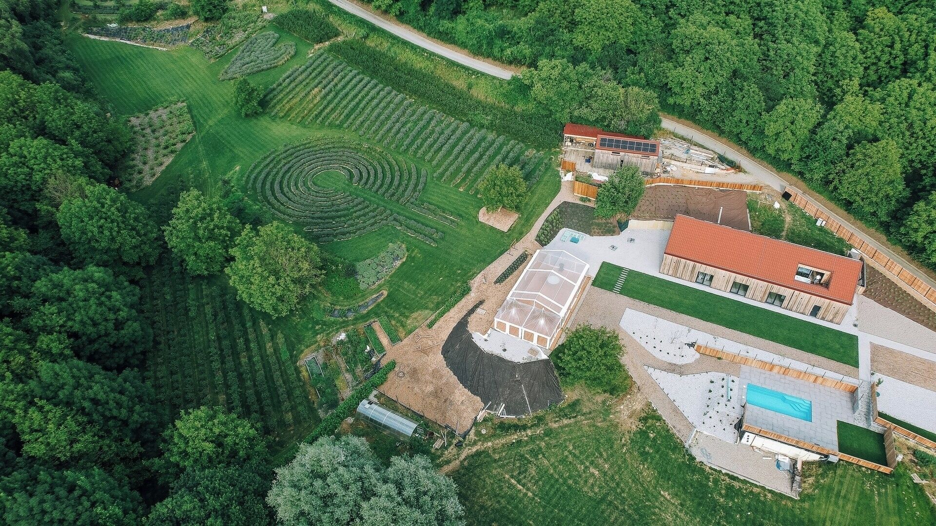 Vista aerea di una proprietà con un ampio giardino, una serra e una piscina.