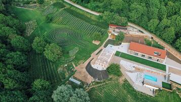 Vista aerea di una proprietà con un ampio giardino, una serra e una piscina.