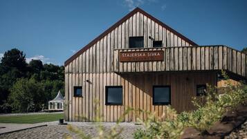 En byggnad av trä med skylten ”Stajerska Sivka Resort”, ett sluttande tak, stora fönster och en grusbelagd mark.