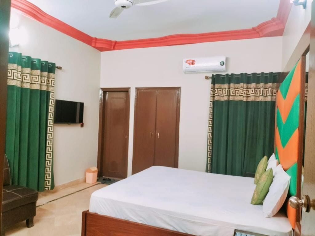 Une chambre à coucher avec un lit, un ventilateur de plafond, une télévision et deux portes.