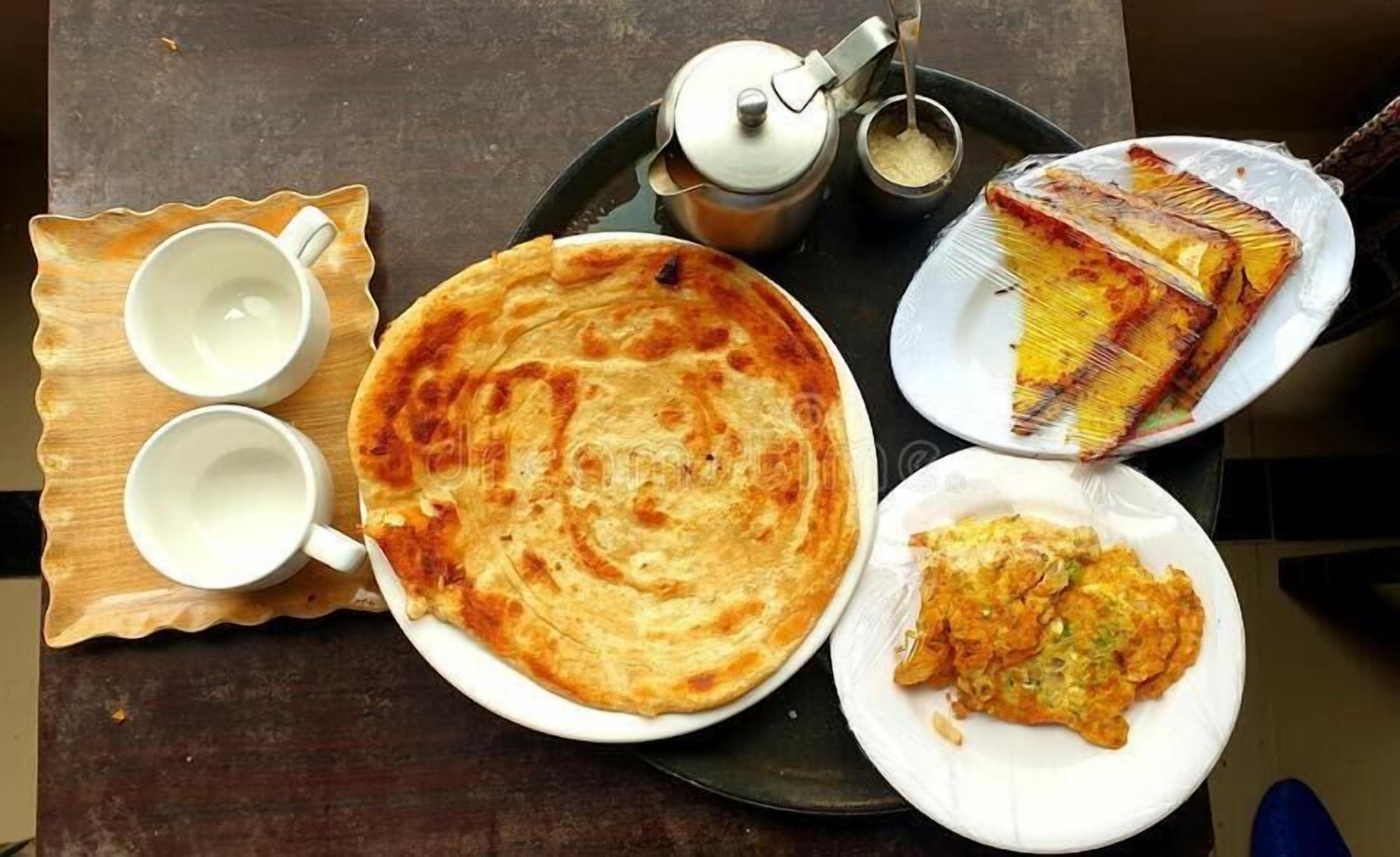 A meal with a flatbread, a slice of cake, and two cups on a tray.