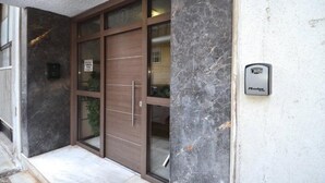 A modern building entrance with a glass door, a marble wall, and a Master keypad.