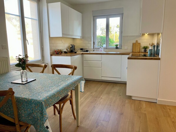 A kitchen with white cabinets, a wooden countertop, and a window.