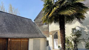 Een gebouw met een schuin dak, een houten poort, een palmboom en een kleine trap naar een deur.