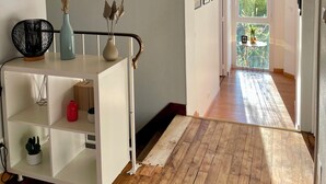 Een modern interieur met een witte console tafel, een houten vloer en een uitzicht door een open deur naar een balkon.