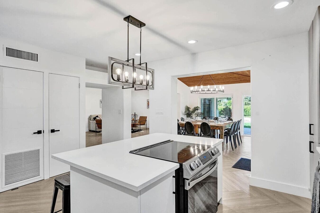 A modern kitchen with a central island, built-in oven, and pendant lighting.