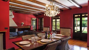 Un espace repas avec une longue table, des chaises en osier et un lustre.