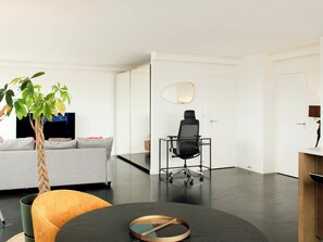 A modern living room with a sofa, a coffee table, a plant, and a desk area with a chair. - Apartment on the 31st floor with balcony in PARIS (Paris)