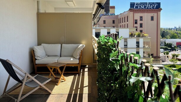 Een balkon met een bank, een kleine tafel en een verticale tuin.