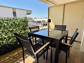 A balcony with a table and chairs, a potted plant, and a view of buildings. - Schiltigheim: 6th Floor Studio with Terrace (Schiltigheim)