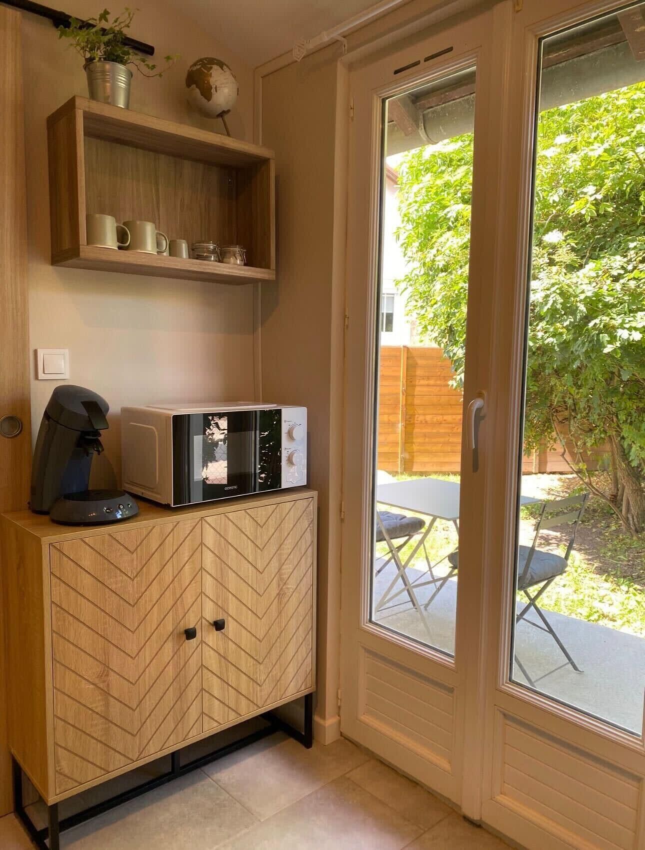 Cocina compacta con microondas, cafetera y un mueble de madera con estampado en chevron.