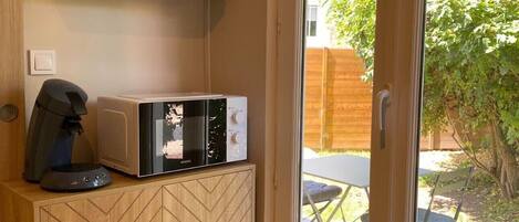 Cocina compacta con microondas, cafetera y un mueble de madera con estampado en chevron.