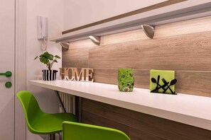 Een moderne keuken met een wit aanrecht, groene stoelen, een potplant en houten letters die 'HOME' spellen.