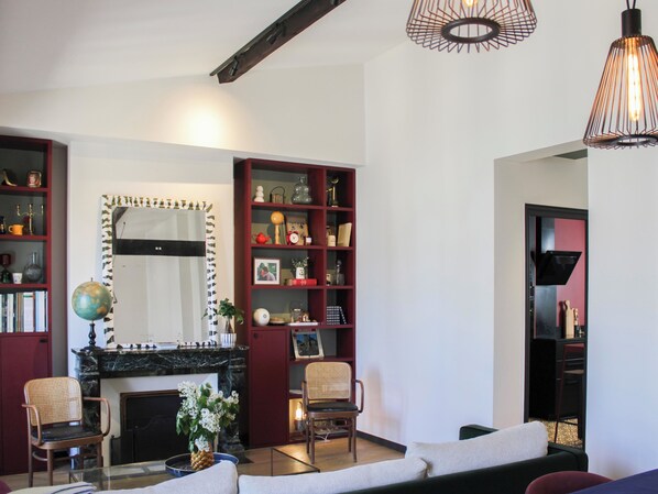 Un salon avec une cheminée, un miroir, une bibliothèque et un canapé.