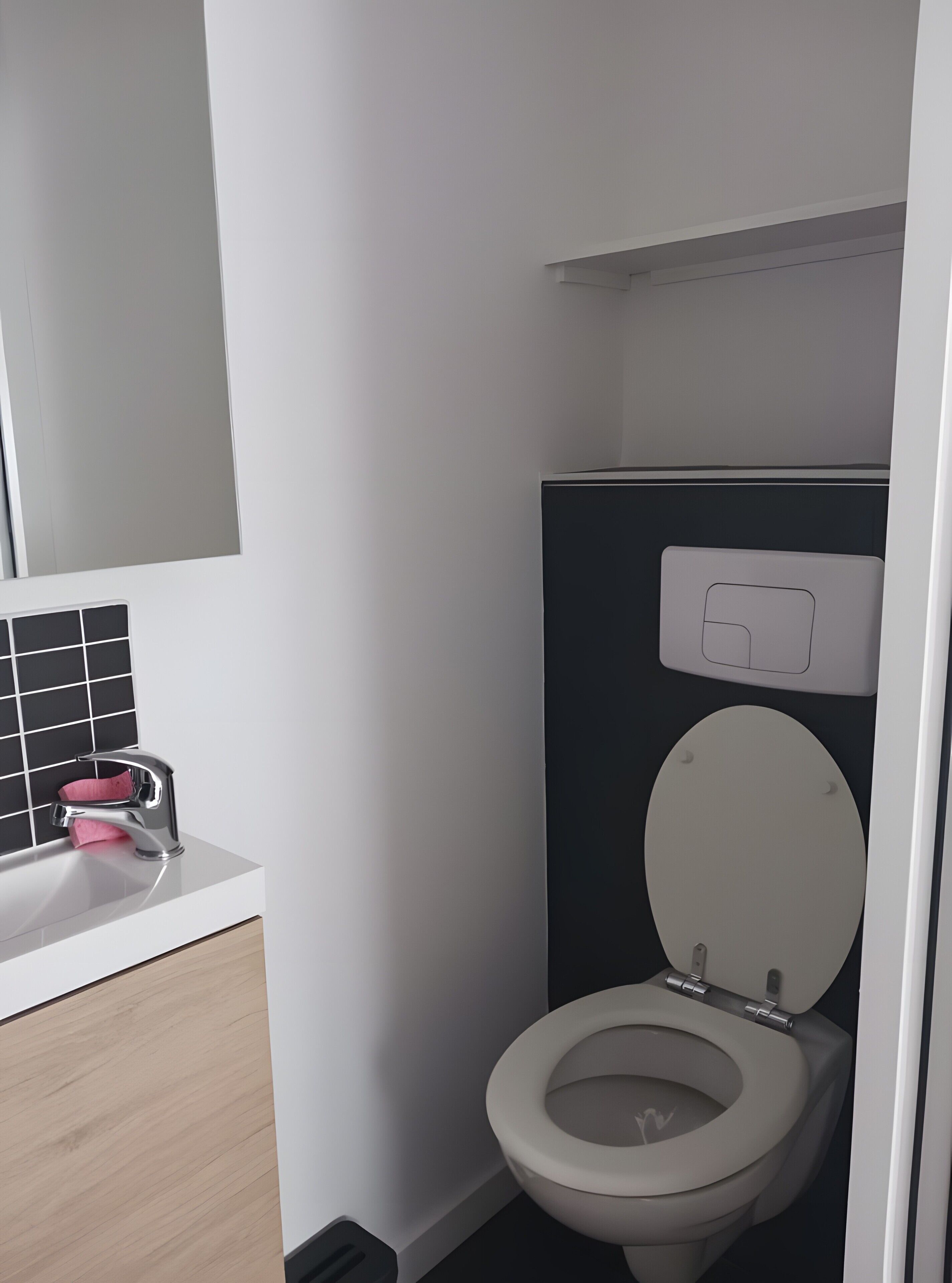 A modern bathroom with a toilet, sink, and mirror.