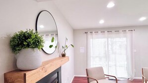 A living room with a fireplace, a large mirror, a potted plant, and two chairs.