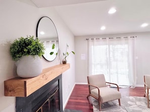 A living room with a fireplace, a large mirror, a potted plant, and two chairs. - Cozy 4BR Single Family Home Near IAD Family-Friendly w/ Workspaces! (Herndon)