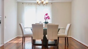 A dining room with a chandelier, a table, four chairs, and a window with curtains.