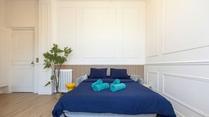 Ein Schlafzimmer mit Bett, Heizkörper, Topfpflanze und einer Tür.