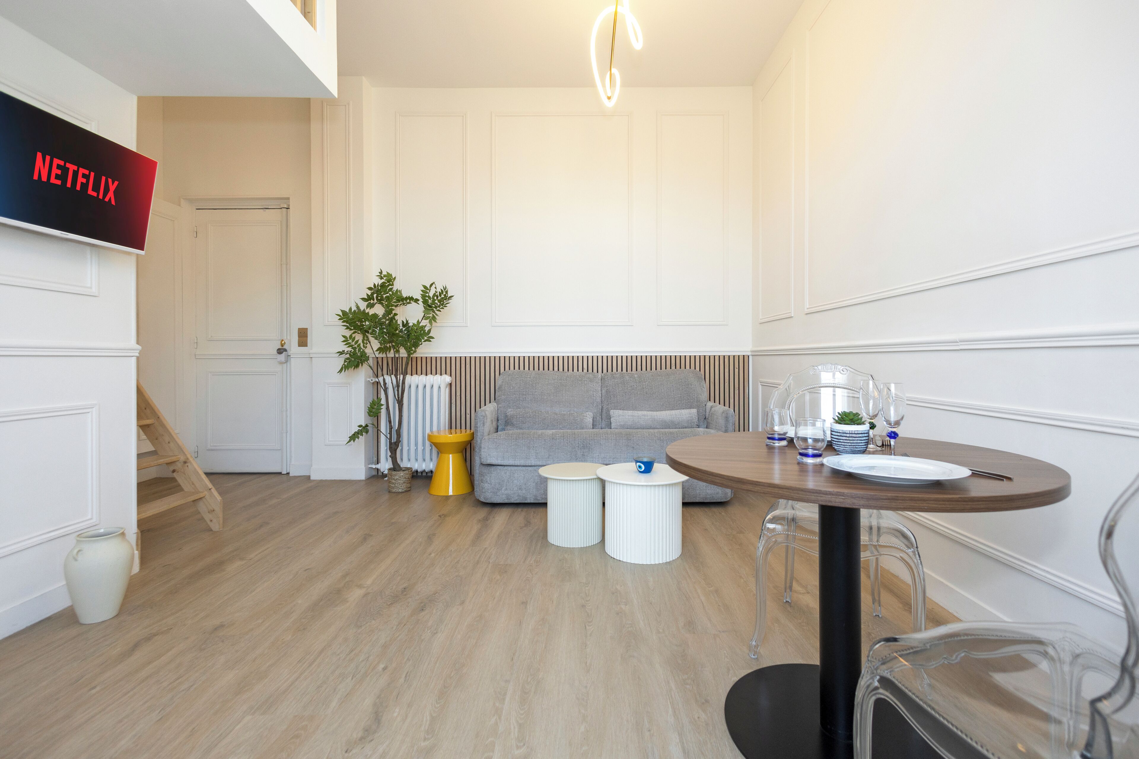 Un salon moderne avec un canapé gris, une table basse en bois et une table à manger avec des chaises.