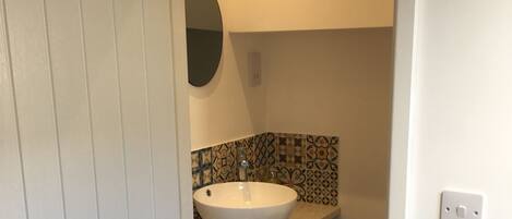 A bathroom with a white sink, a mirror, patterned tiles, and dark flooring.