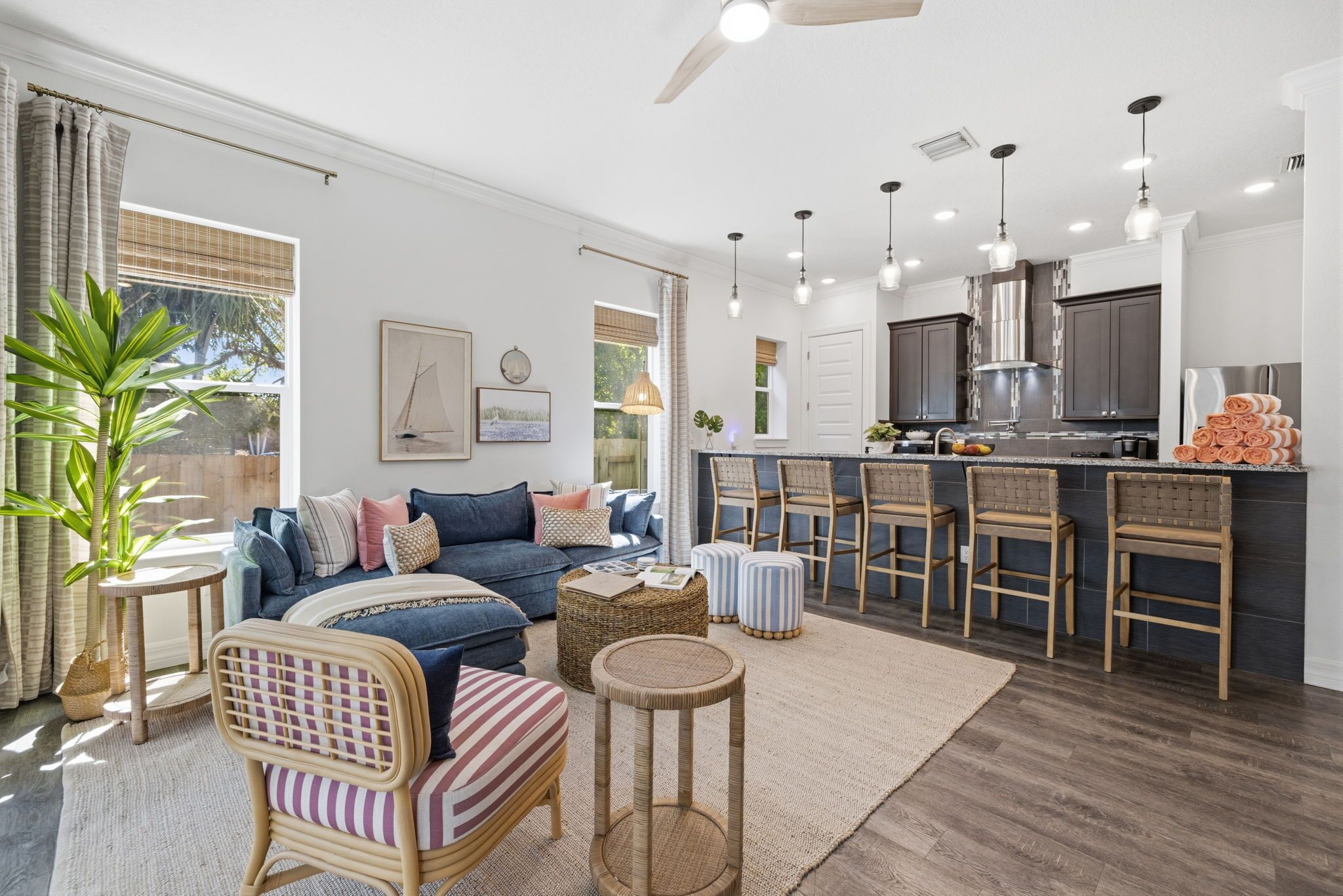 Una sala de estar moderna con un sofá, sillas, una mesa de centro y una zona de cocina con taburetes de bar.