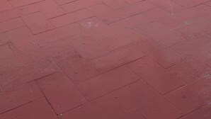 Kattoterassi, jossa on punaisella päällystetty lattia, valkoinen ja punainen seinä sekä näkyvillä oleva sähköjohto.