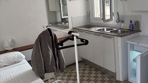 Kompakti hotellihuone, jossa on sänky, pieni keittokomero, suihkulla varustettu kylpyhuone ja ikkuna, josta tulee luonnonvaloa.