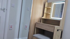 A room with a wooden vanity, a mirror, and a bench.