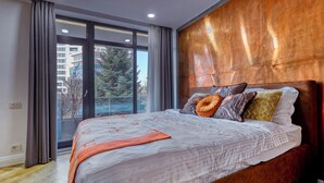 Ein Schlafzimmer mit einem großen Bett, einem Holz-Kopfteil, Blick durch eine Schiebetür und einem Fenster.