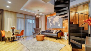 Ein modernes Wohnzimmer mit einer Couch, Sesseln, einem Esstisch, einem Teppich, einer Weltkarte an der Wand und einer Wendeltreppe.