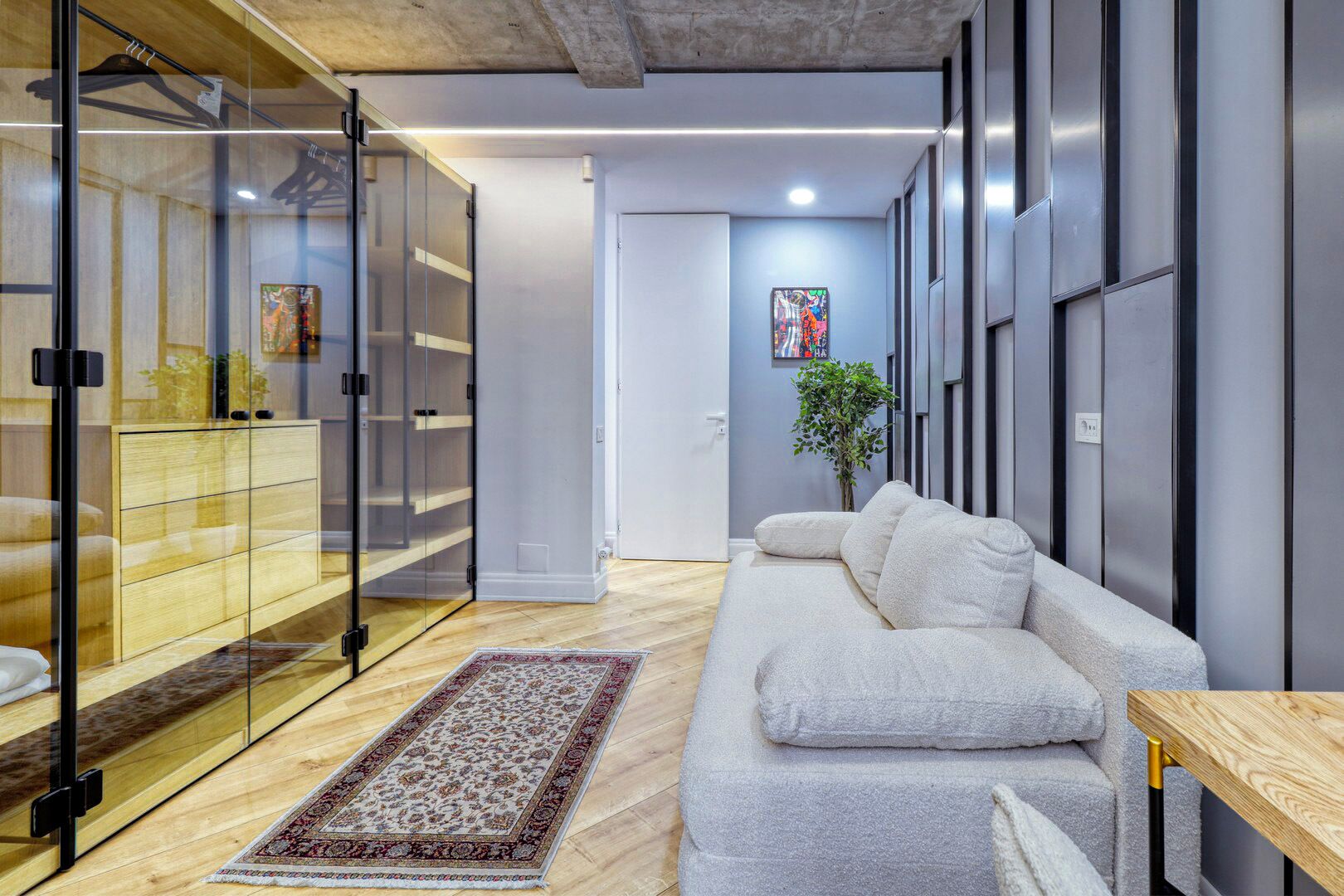 Un interior moderno con un sofá, un aparador de vidrio y una planta.