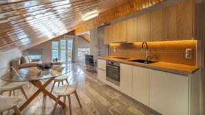 Eine moderne Küche mit Holzschränken, einem Glastisch und Blick ins Freie.