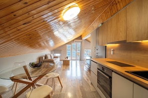 A modern kitchen with wooden cabinetry, a glass dining table, and a view to the outside.