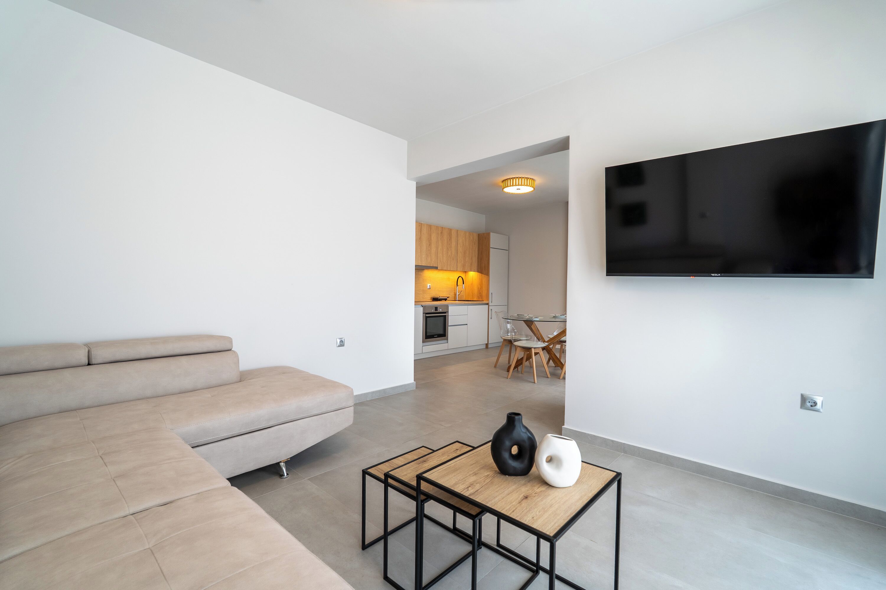 A modern living room with a sofa, a coffee table, and a flat-screen TV mounted on the wall.