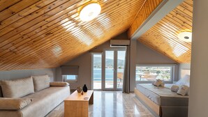 Ein geräumiges Schlafzimmer im Loft-Stil mit Holzbalkendecke, einem großen Bett, einer Couch und Meerblick.