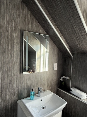 A bathroom with a white sink, a mirror, and a towel rack.