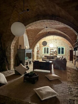 A cozy interior with a stone archway, a fireplace, a sofa, and a coffee table. - Podere Le Marene (Baschi)