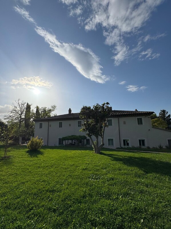 A two-story building with a flat roof, surrounded by a well-maintained lawn and trees. - Podere Le Marene (Baschi)