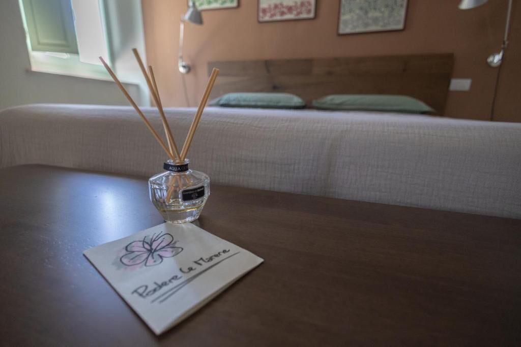 Ein Zimmer mit einem Bett, einem Nachttisch mit einem Reed-Diffusor und einer Karte mit einem Blumenmuster.