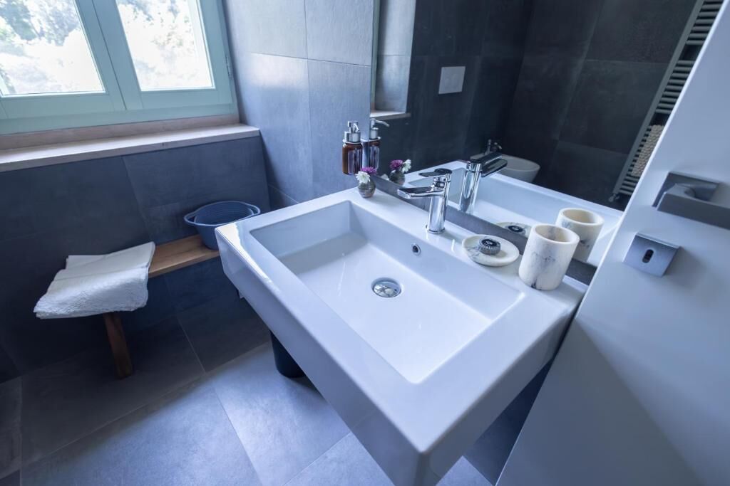 Een moderne badkamer met een groot wastafel, een spiegel en een raam.