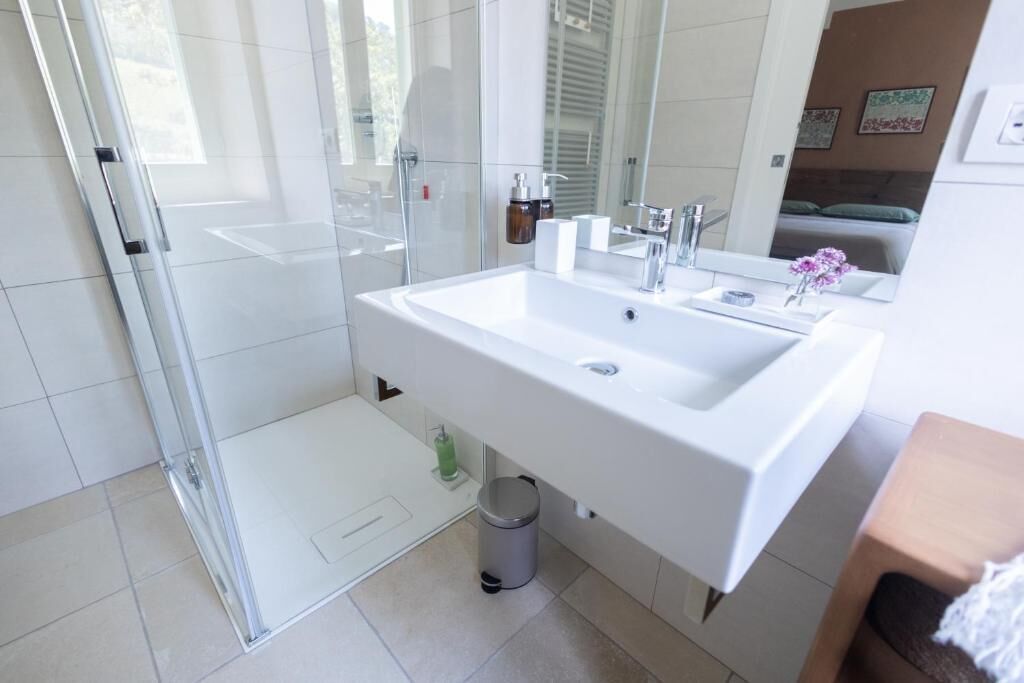 Un baño moderno con cabina de ducha de vidrio, un lavabo blanco y un espejo.