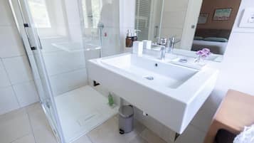Un baño moderno con cabina de ducha de vidrio, un lavabo blanco y un espejo.