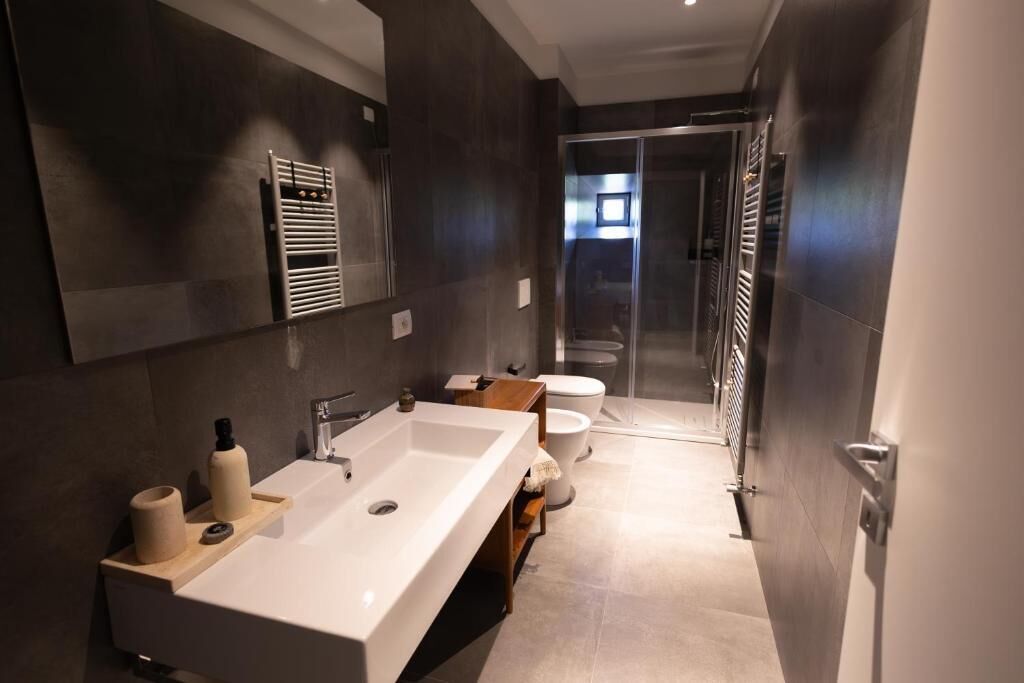 A modern bathroom with a large sink, toilet, and shower.