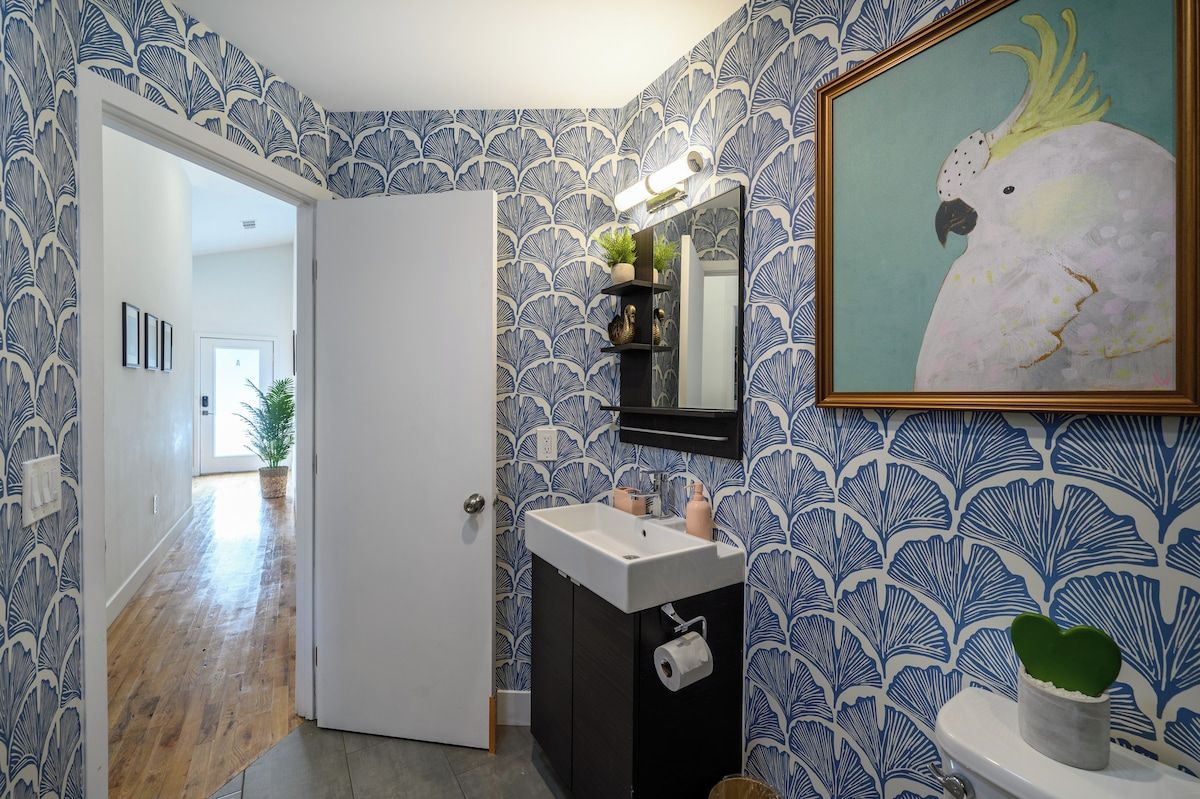A bathroom with a white sink, a mirror, and a framed bird painting.