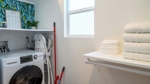 Ein Waschbereich mit Waschmaschine, Wäscheständer und Fenster.