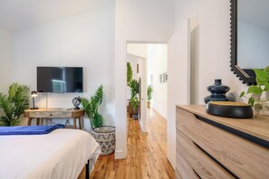 Open bedroom with a TV, workspace and leafy decor flowing into the hallway - 6mile to Disney • OC • 5mi to airport • Garage (Santa Ana)