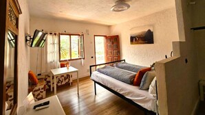Ein Schlafzimmer mit einem Bett, einem Schreibtisch, einem Sessel und einem Fernseher.
