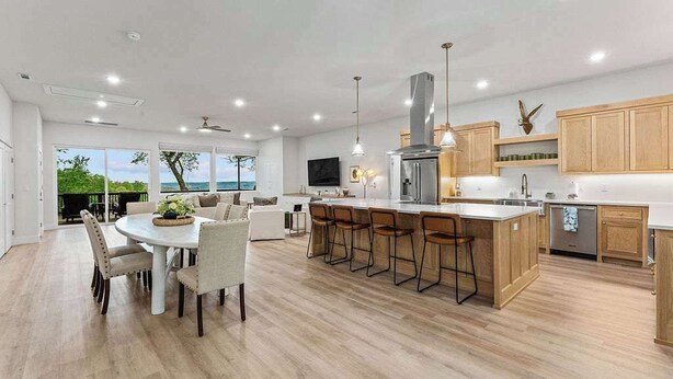 Una cocina moderna con una isla central, armarios de madera y un ventanal con vistas panorámicas.
